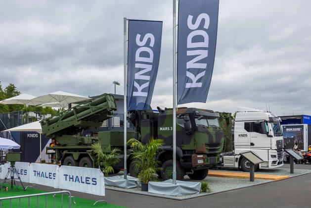 Trade visitor day at ILA Berlin 2026, Berlin, 12 06 2026 The MARS 3 multiple rocket launcher system from KNDS is on display in the outdoor area of the exhibition grounds KNDS is also presenting another vehicle and a truck Barriers with Thales lettering can be seen in the foreground Schöneberg Berlin ExpoCenter Airport Brandenburg Germany 20260612-286A9961-M4000