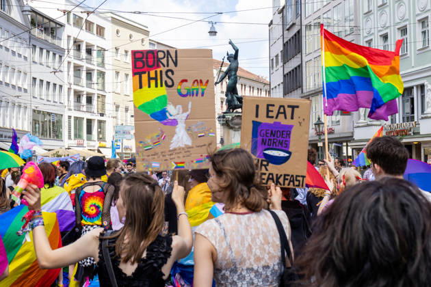 Augsburg, Bavaria, Germany June 13, 2026: Participants carrying rainbow flags and wearing colorful costumes take part in Christopher Street Day (CSD) in Augsburg. The parade through the city center promotes the rights of LGBTQ+ people as well as social diversity and tolerance. Participants carrying rainbow flags and signs reading: BORN THIS GAY and I EAT GENDER NORMS
