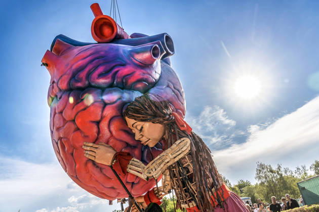 Eröffnung des Tollwood Sommerfestivals 2026, Little Amal begleitet die Festival-Eröffnung, die berühmte 3,5 Meter große Puppe, die das zehnjährige syrische Flüchtlingsmädchen Amal verkörpert, Amal umarmt die überlebensgroße Skulptur eines Deutschland, München, 19. Juni 2026, Eröffnung des Tollwood Sommerfestivals 2026, Little Amal begleitet die Festival-Eröffnung, die berühmte 3,5 Meter große Puppe, die das zehnjährige syrische Flüchtlingsmädchen Amal verkörpert, wurde weltweit zu einem Sinnbild für Hoffnung und Menschlichkeit, Little Amal umarmt die überlebensgroße Skulptur eines anatomischen Herzens, das Symbol des Festivals, das Tollwood ist ein multikulturelles Festival, das im Sommer im Olympiapark sta