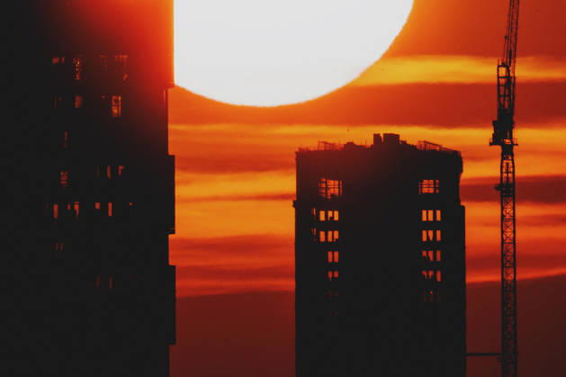 The setting sun is visible behind a new building with a crane in Berlin, June 19, 2026. A heat wave is currently affecting all of Germany. Berlin, Germany,detected_source_language Copyright: xFlorianxGaertnerx