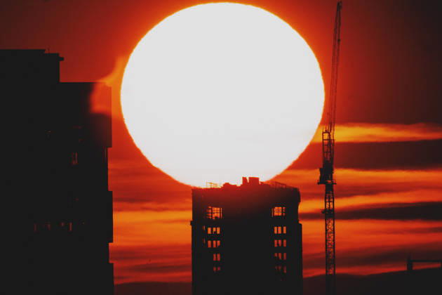The setting sun is visible behind a new building with a crane in Berlin, June 19, 2026. A heat wave is currently affecting all of Germany. Berlin, Germany,detected_source_language Copyright: xFlorianxGaertnerx