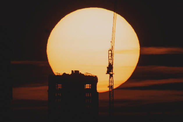 The setting sun is visible behind a new building with a crane in Berlin, June 19, 2026. A heat wave is currently affecting all of Germany. Berlin, Germany,detected_source_language Copyright: xFlorianxGaertnerx