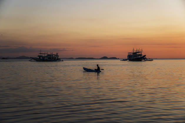 A male paddles a small boat during a tropical sunset in El Nido model released, Symbolfoto, PNAF07101