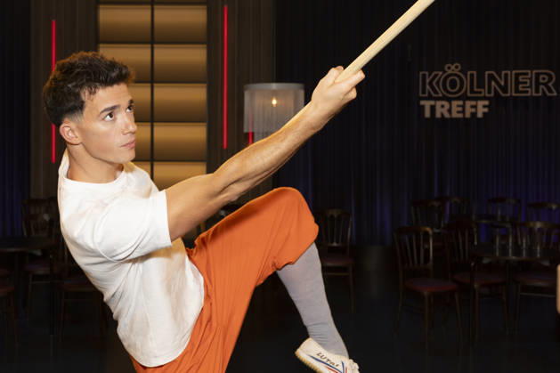 Shaolin Kid Sacha WENK, holding a Bo staff, focused, portrait, guest on the TV show Koelner Treff on WDR television, recorded on July 10, 2026, Aired on August 7, 2026
