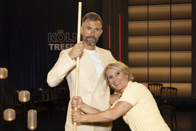 Host Micky BEISENHERZ (left) and host Susan LINK (right) hold onto a Shaolin Bo staff; portrait, portrait, from the TV show Koelner Treff on WDR television; recorded on July 10, 2026; Aired on August 7, 2026