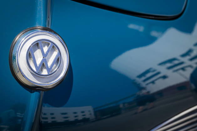 Close-up of the VW logo on the hood of a Karmann Ghia Coupé. The VW Osnabrück plant is reflected in the blue paint. 11 07 2026. Symbolic image of VW Osnabrück