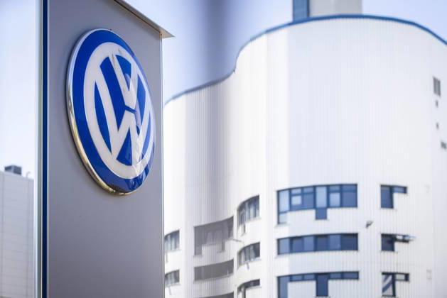 Stock photo: Volkswagen Osnabrück—VW logo at Gate 2, photographed through the fence with a white factory building in the background; VW plant in Osnabrück, July 11, 2026; stock photo: VW Osnabrück