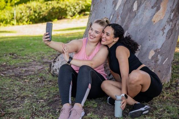 Diverse female friends posing for selfie while sitting on grass under tree in park using smartphone, model released, property released, 17.04.2025 06:00:00, 6702435 Copyright: xIDS-250923_1xcreatorid:x0x 6702435