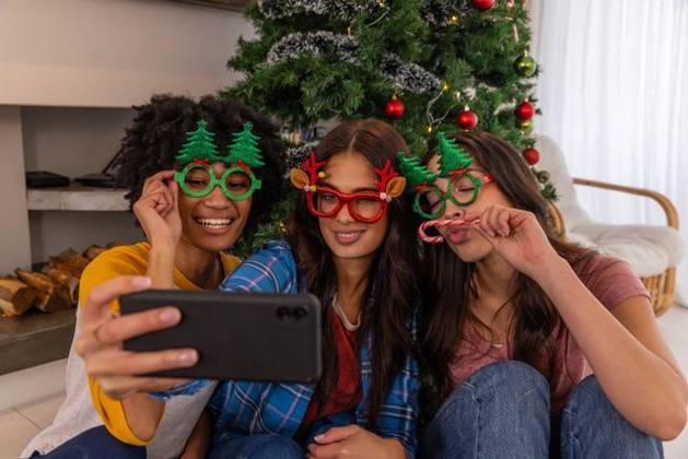 Diverse female friends posing for selfie on living room floor with smartphone near christmas tree, model released, property released, 26.09.2024 06:00:00, 6523222 Copyright: xIDS-250922_1xcreatorid:x0x 6523222