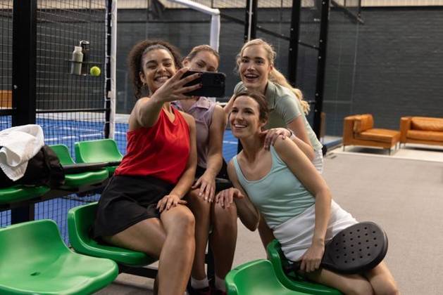 Diverse female friends posing for selfie at padel court in sportswear holding smartphone and racket, model released, property released, 18.06.2025 06:00:00, 6882332 Copyright: xIDS-260612_2xcreatorid:x0x 6882332