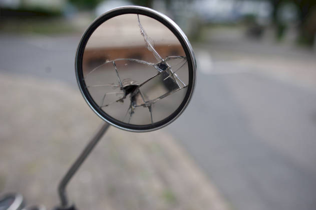 Flensburg, Schleswig-Holstein: Close-up of a round, chrome-plated rearview mirror from a scooter. The mirror glass is severely shattered, has deep cracks, and a hole in the center. Photo taken on July 25, 2026, in Flensburg