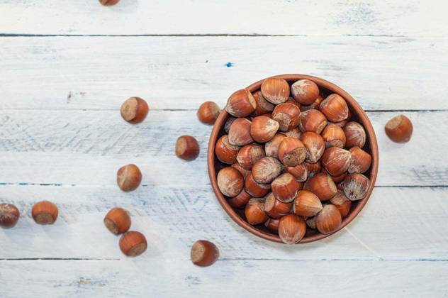 Hazelnuts in shell in brown clay bowl on a white wooden background, top view Copyright: xndankox Panthermedia74711094.jpg
