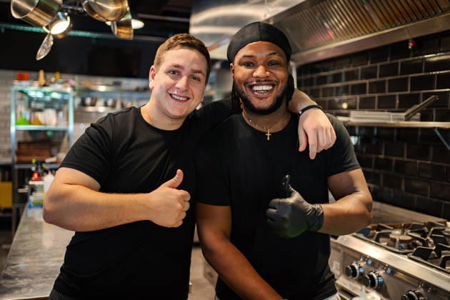 Fröhliche Mitarbeiter in einer Restaurantküche, die den Daumen hochhalten Two diverse friends smiling in professional kitchen showing approval (License=RF) ,model released, Symbolfoto Copyright: xZoonar.com JelenaxCvetkovicx 25376767 ,model released, Symbolfoto ,property released