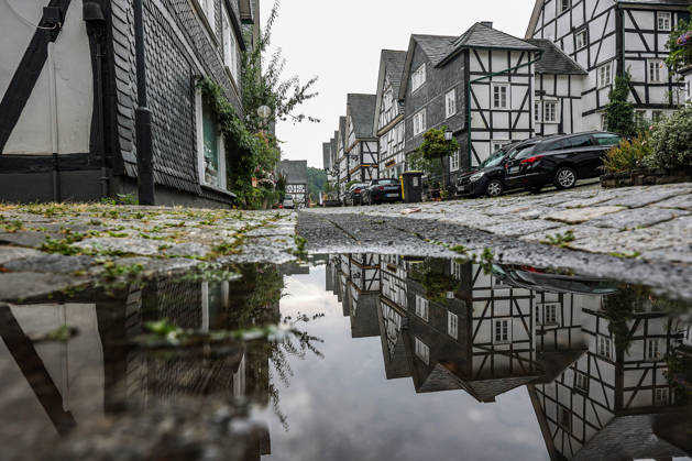 Weather Change: A rare sight in the Siegerland region in recent weeks. After days and weeks of dry, hot weather, the new week is starting off wet and relatively cool. The historic old town of Freudenberg with its half-timbered houses. The haehouses are reflected in a puddle. Summer in the Siegerland region on August 17,