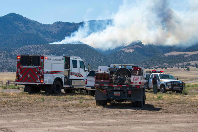 August 23, 2026, Elberta, Utah, USA: A plume of thick smoke rises into the sky above a mountain ridge as the Big Mountain Fire burns southwest of Elberta, Utah, United States, on August 23, 2026. A line of emergency response vehicles can be seen staged along a dirt road below the active wildland blaze. Elberta USA - ZUMAm292 20260823_znp_m292_001 Copyright: xCharlesxMcClintockxWilsonx