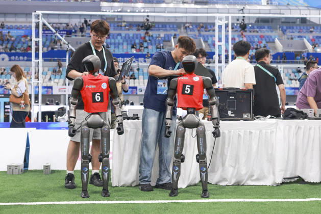 BEIJING, CHINA - AUGUST 23: Technicians check robot players during the quarterfinal match of the soccer event - 5v5 Large Size Group on day 2 of the 2nd World Humanoid Robot Games at National Speed Skating Oval on August 23, 2026 in Beijing, China.  Copyright: xChinaxNewsxServicex 111661701845