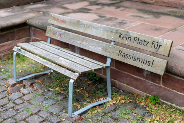 God Loves Diversity A wooden bench with the colorful engraved phrases *God Loves Diversity* and *No Place for Racism* from the *Dein Werk* initiative will be placed in front of St. Gallus Church in Ladenburg, Baden-Württemberg, on August 17, 2026, Germany. With such specially designed benches in public spaces, ch