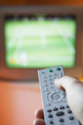 Closeup of female hand using remote control in front of TV model released Symbolfoto Copyright: xmoodboardx Panthermedia75412790.jpg