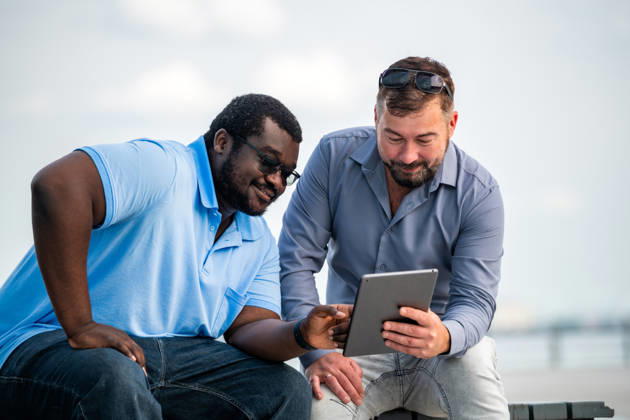 Two diverse male friends using a digital tablet outdoors Saint Petersburg, Saint Petersburg, Russia CR_YFCG260824-2080923-01 ,model released, Symbolfoto ,property released