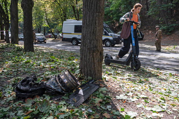 A woman pushes a rented electric scooter past the fragments of a Russian drone found on Parkova Doroha Street in the Pecherskyi district after a Russian attack, Kyiv, Ukraine, August 27, 2026. Since the night of August 27, the Russian army has been striking the Ukrainian capital with ballistic missiles and drones. Overnight and daytime attacks and falling debris caused destruction across several districts of Kyiv, damaging residential buildings, cars, gymnasium premises and a medical facility. (Photo by Danylo Antoniuk Ukrinform) Forensic experts examine wreckage of Russian drone in Kyiv  Copyright: xDanyloxAntoniukx