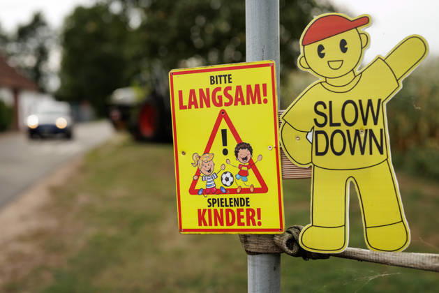 Please Slow Down—Children Playing : A warning sign reading * Please Slow Down—Childre