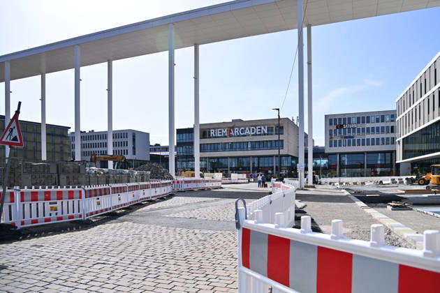Redesign of Willy Brandt Platz at the Riem Arcaden: Sealed Surfaces Are Being Converted into Green Spaces Construction work is underway to redesign Willy Brandt Platz in front of the Riem Arcaden in Munich. As part of the redesign, previously sealed surfaces will be unsealed and replaced with green spaces. Construction barriers