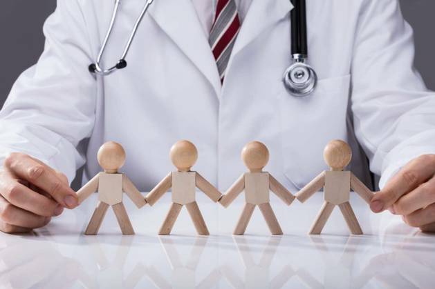 Close-up Of Doctor Holding Hand Of Wooden Figures Standing In A Row model released Symbolfoto Copyright: xAndreyPopovx Panthermedia76468892.jpg
