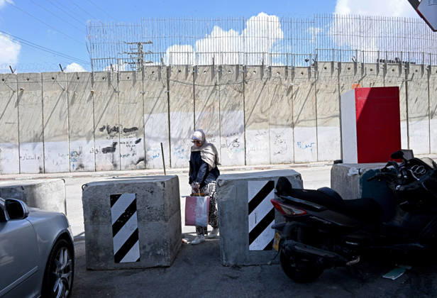 A Palestinian woman carries groceries through barriers near the Israeli separation wall that cuts through Beit Hanina in East Jerusalem on Sunday, August 30, 2026. Thousands of Palestinian residents of East Jerusalem are forced to go through time consuming checkpoints to reach their schools, jobs, hospitals and visit family because of the separation barrier.  JER2026083008 DEBBIExHILL