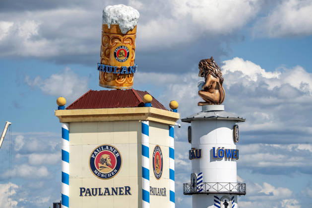 Oktoberfest 2026, The Paulaner and Löwenbräu towers already dominate the white-and-blue Bavarian sky above the Theresienwiese, three weeks before Oktoberfest begins on September 19, Munich, August 31, 2026, Germany, Munich, August 31, 2026, Oktoberfest 2026: The Paulaner and Löwen
