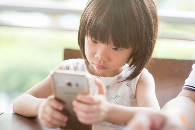 Asian child playing smart phone at cafe. Natural light outdoor lifestyle. model released Symbolfoto Copyright: xszefeix Panthermedia77110000.jpg