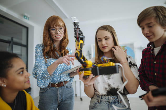 Teen students building robotic arm together during STEM class. High school students working on robotics project in science classroom. model released