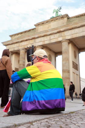 A participant wearing a rainbow-colored jacket waits for the rally to begin. The event, held under the slogan Time to Act: Stop the AfD, is taking place in Berlin at the Branden Copyright: epd-bild HansxScherhaufer epd-Demo_Landtagswahl10-kopieren