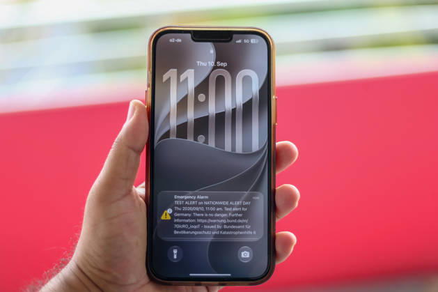 Germany, Europe: Close-up of a smartphone held in a hand, displaying a test alert for the nationwide Alert Day. The lock screen shows alerts from the Federal Office for Civil Protection and Disaster Assistance (BBK), as well as the time and date. Stock image related to civil protection, cell broadcast, warning systems, civil protection, and emergency commun Copyright: xAymanxAlahmedx