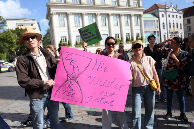 Protesters holding a sign reading Never Again stand next to an hourglass symbolizing democracy during a demonstration calling for the Federal Constitutional Court to review far-right parties, Alter Markt, Potsdam, September 12, 2026. Protest in Potsdam