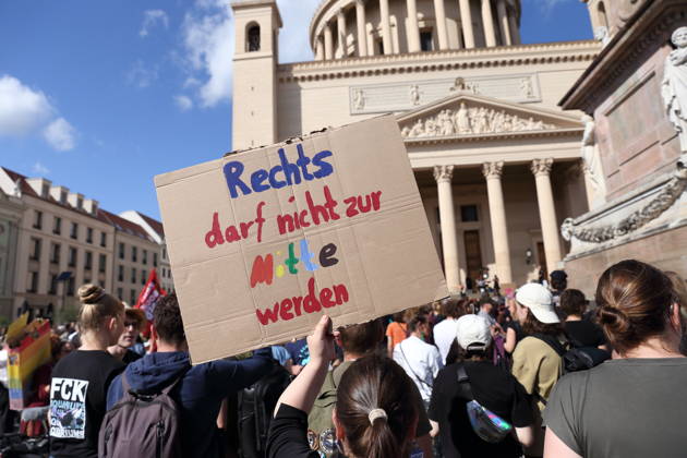 A female protester holding a sign that reads The Right Must Not Become the Center during a demonstration calling for the Federal Constitutional Court to review far-right parties, Alter Markt, Potsdam, September 12, 2026—Protest in Potsdam