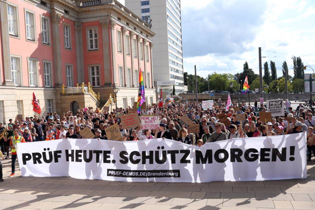 Protesters carrying a banner reading Review today, Schütz tomorrow march around the state parliament during a demonstration calling for the Federal Constitutional Court to review far-right parties, Alter Markt, Potsdam, September 12, 2026. Review demonstration in Potsdam