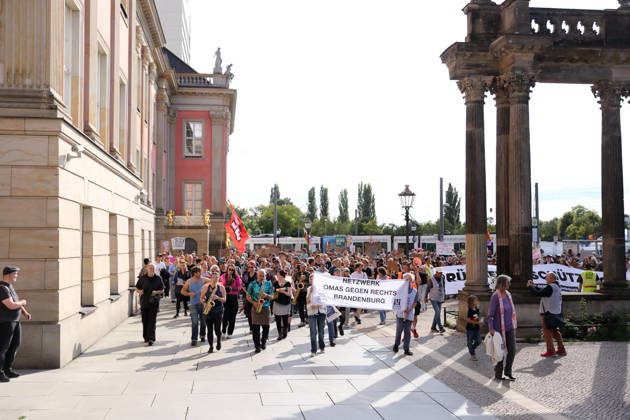 Protesters march around the state capitol building carrying a banner reading Netzwerk Omas gegen Rechts Brandenburg during a demonstration calling for the Federal Constitutional Court to review far-right parties, Alter Markt, Potsdam, September 12, 2026. Protest in Potsdam