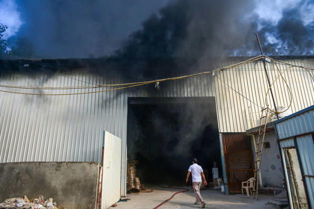 NEW DELHI, INDIA - SEPTEMBER 13: Firefighters work to extinguish a massive blaze at a plywood warehouse in Dallupura, East Delhi, as thick plumes of smoke billow into the sky and remain visible from several kilometres away, on September 13, 2026 in New Delhi, India. The fire department received a call about the blaze at 3.20 pm, following which 12 fire tenders were rushed to the spot. Firefighters were present at the site and were working to control the blaze. (Photo by Sunil Ghosh Hindustan Times ) Massive Fire Breaks Out At Delhi Plywood Warehouse, 12 Fire Tenders Rushed