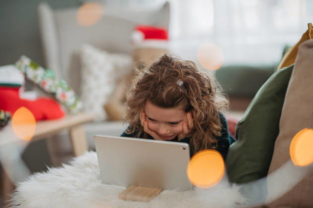 Little girl enjoying new tablet received as Christmas present at home. Excited young girl exploring new tablet during Christmas holidays. model released