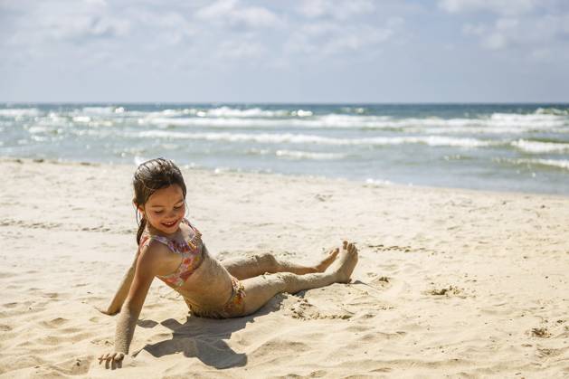 Ein süßes kleines Mädchen im Badeanzug sitzt am sandigen Strand, mit Sand bedeckt, während hinter ihr die Meereswellen brechen? ein Bild, das die Freude an den Sommerferien und unbeschwerte Kindheitserinnerungen verkörpert Ein süßes kleines Mädchen im Badeanzug sitzt am sandigen Strand, mit Sand bedeckt, während hinter ihr die Meereswellen brechen ? ein Bild, das die Freude an den Sommerferien und unbeschwerte Kindheitserinnerungen verkörpert Copyright: imageBROKER AnnaxLurye ibxiqx18673121.jpg ,model released, Symbolfoto ,property released
