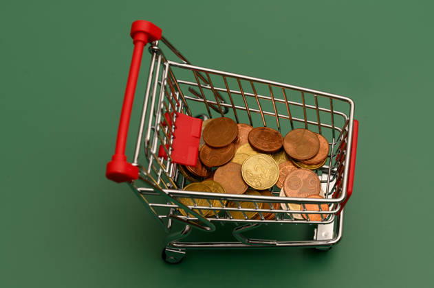 Mini shopping cart with coins seen from above, Waldsee, Germany, September 14, 2026. Top view of a mini shopping cart with Euro coins on a green background. Stock image representing loose change, saving, and household budget.
