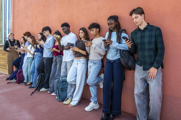 Vielfältige Gruppe von Teenagern der Generation Z, die in einer Reihe stehen, individuell in ihren Mobiltelefonen versunken sind und die Sucht nach sozialen Medien und digitaler Kommunikation symbolisieren Diverse group of gen z teenagers standing in a line, individually absorbed in their mobile phones, symbolizing social media addiction and digital communication Copyright: imageBROKER UnaixHuizi ibxuhu19078250.jpg ,model released, Symbolfoto ,property released