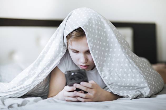 Süßer kleiner Junge mit Smartphone liegt auf dem Bett unter dem Cover zu Hause Cute little boy with smartphone lying on bed under cover at home Copyright: imageBROKER ZulfiiaxIshmukhameto ibxiqx19060611.jpg ,model released, Symbolfoto ,property released