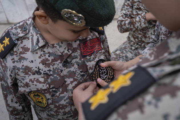 Opening Ceremony Of Second City-Square Military Training Camp An Iranian schoolboy wearing an Iranian Army military uniform helps his friend attach a badge for self-sacrificing forces as they prepare to take part in the opening ceremony of the second city-square military training camp in downtown Tehran, Iran, on October 3, 2026. The second City-Square Military Training Camp for the self-sacrificing forces was established by the Basij paramilitary force, with personnel from the Islamic Republic of Iran Army responsible for training the volunteers. Tehran Tehran Iran Copyright: xMortezaxNikoubazlx originalFilename: nikoubazl-openingc261003_npccq