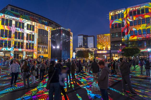 Essen Light Festival, in the city center; the light installation Diving in the Sea of Colors by Berlin-based artist Daniel Margraf illuminates the buildings on the large Kennedy Platz; visitors become part of the light art installation; North Rhine-Westphalia, Germany; Essen Light Festival