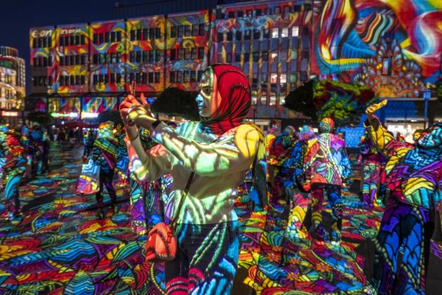 Essen Light Festival, in the city center; the light installation Diving in the Sea of Colors by Berlin-based artist Daniel Margraf illuminates the buildings on the large Kennedy Platz; visitors become part of the light art installation; North Rhine-Westphalia, Germany; Essen Light Festival