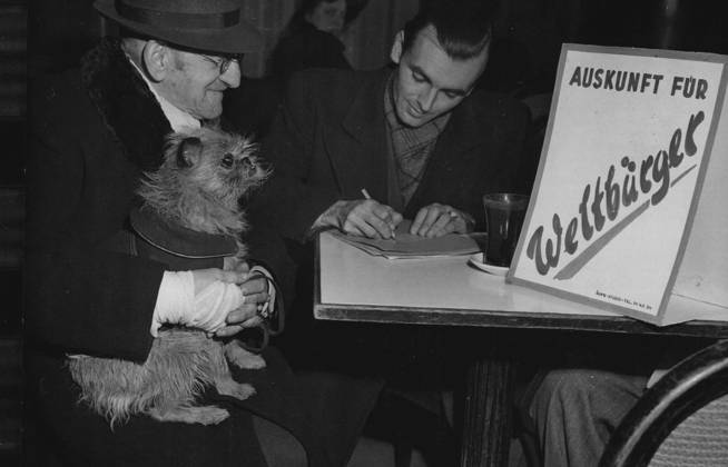 Information for World Citizens ... Reads a sign standing on the table of a Berlin coffeehouse as an aged Berliner and his dog apply to become World Citizens . The application was made to Dettmar H. Otto who claims to be Berlin World Citizen No. 1. Shortly after this picture was made January 25. The owner of the coffeehouse threw the World Citizens out because their organization is not registered with the police. January 28, 1948. (Photo by Associated Press Photo).  Copyright: xAssociatedxPressxPhotox 5513-76011828