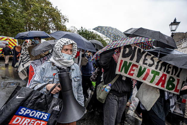 Pro-Israeil counter protestors challenge pro-Palestine demonstrators in London, UK - 7 OCT 2026. A woman seen holding a megaphone in front of pro-Palestine activists from London universities shielding themselves behind a protective wall of umbrellas while holding banners on their march . Pro-Palestine activists from Central London Universities chose the 3rd anniversary of the October 7th attack by Hamas to protest against Israel’s war on Gaza. They clashed en route with pro-Israeli counter protestors. The demonstration was arranged by an inter-uni coalition that includes King’s College and LSE. London United Kingdom Copyright: xLabxMox xSOPAxImagesx LabMO_Oct_7th_Uni_Protest_SOPA_5