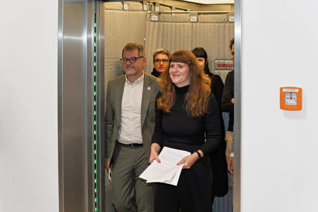Berlin, October 8, 2026—Kerstin Wolter Ehling of Die Linke (front) and Werner Graf of Alliance 90 The Greens (left) emerge from the elevator following preliminary talks with Die Linke Berlin, Alliance 90 The Greens Berlin, and the SPD Berlin, step out of the elevator to deliver a joint press statement in the foyer of the Haus der Statistik. Press statement by The Left, The Greens, and the SP