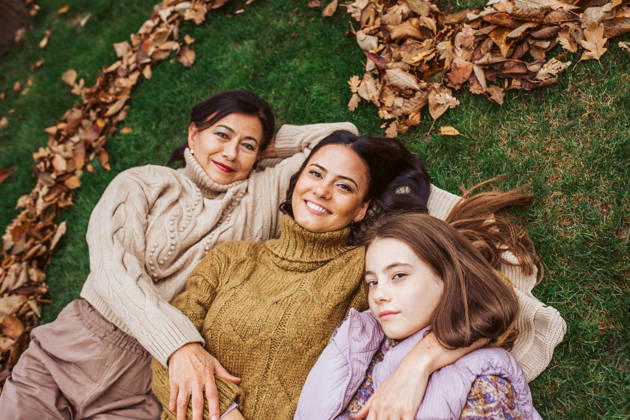 Mother, grandmother and daughter, laying on grass in the middle of heart from leaves. Portrait of mother, grandmother and daughter, laying on grass in the middle of heart from leaves. model released
